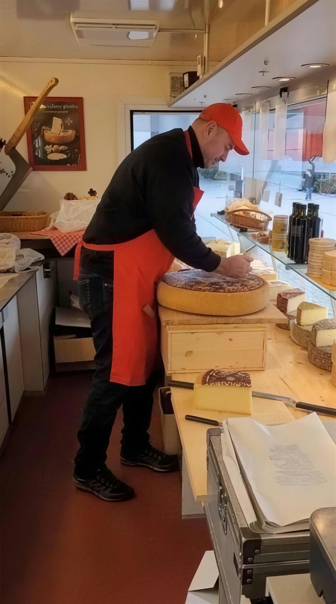 Jochen Kurz schneidet im Käsewagen frischen Käse vom Laib